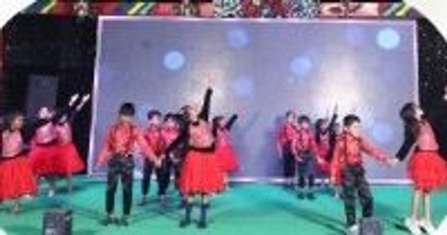 Children performing a group dance on stage during the annual celebration at Sunrise Convent School