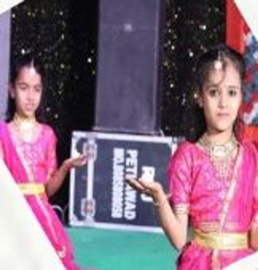 Two pupils in pink traditional costume performing a classical dance on stage