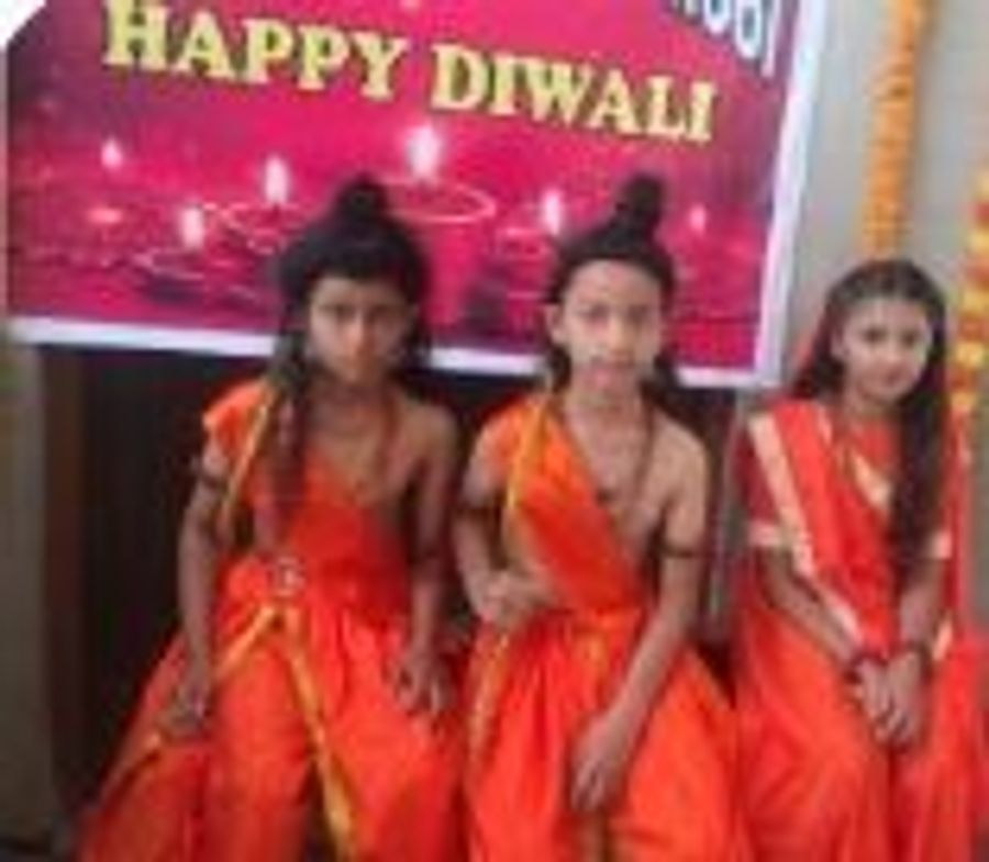 Children in orange outfits dancing in front of a festival backdrop