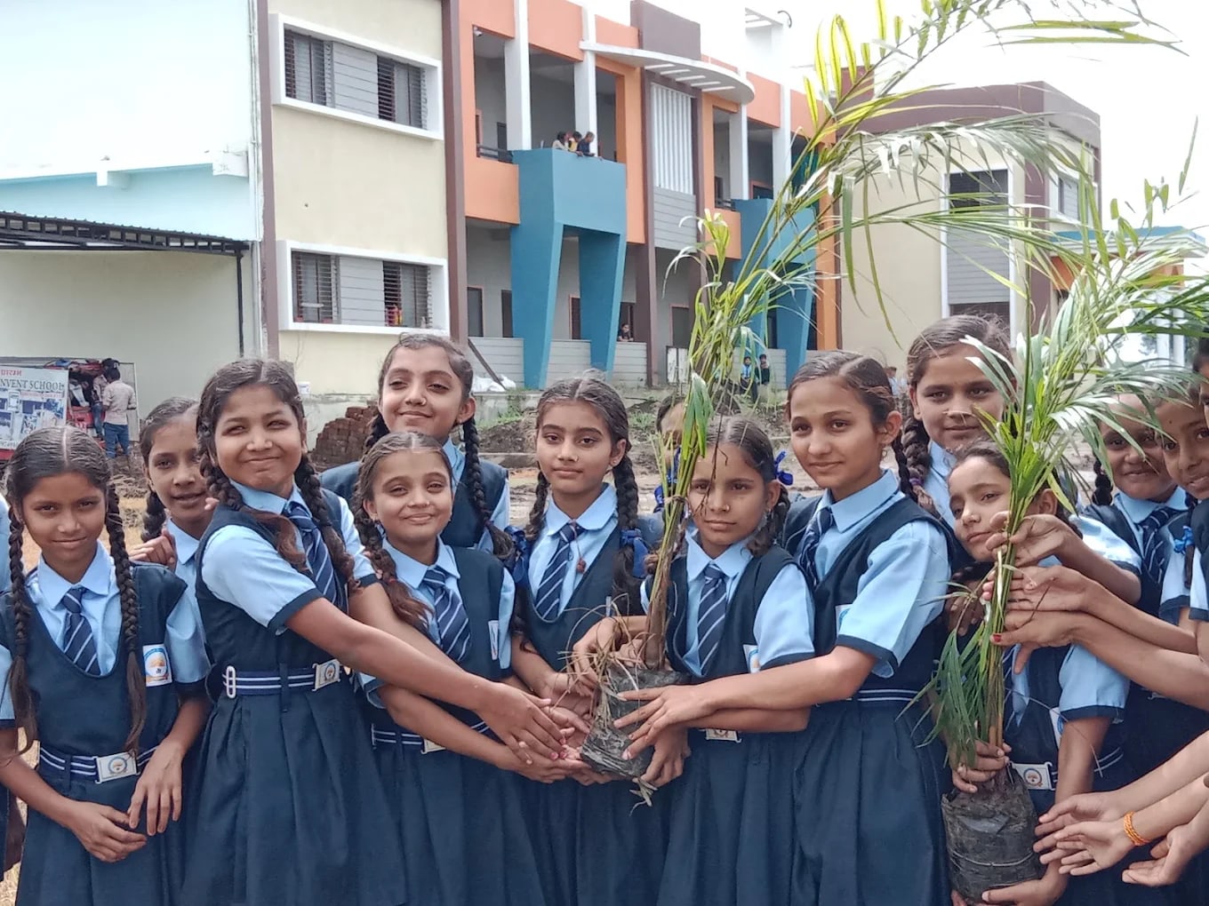 Students in school uniform planting saplings in front of the Sunrise Convent School building at Bhensola